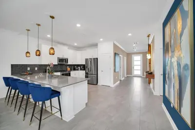 a kitchen with white cabinets and blue bar stools at 9 Bed Pool Home Storey Lake Resort! home in Kissimmee