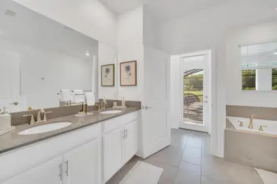 a white bathroom with two sinks and a window at 9 Bed Pool Home Storey Lake Resort! home in Kissimmee