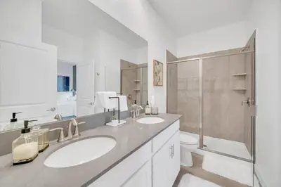 a white bathroom with two sinks and a shower at 9 Bed Pool Home Storey Lake Resort! home in Kissimmee