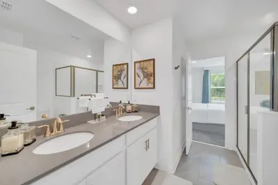 a white bathroom with two sinks and a shower at 9 Bed Pool Home Storey Lake Resort! home in Kissimmee