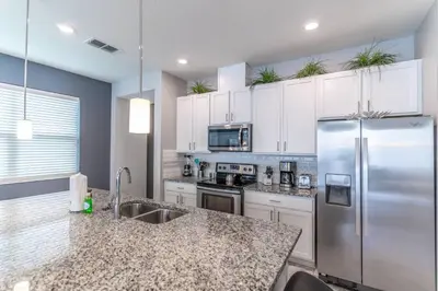 a kitchen with white cabinets and a stainless steel refrigerator at 5134 Compass Bay in Kissimmee