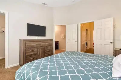a bedroom with a bed and a flat screen tv at Minutes to Disney, Free Water Park & Private Pool in Orlando