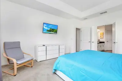 a bedroom with a blue bed and a chair at Modern 6BR Home - Pool BBQ Hot Tub - Near Disney in Kissimmee