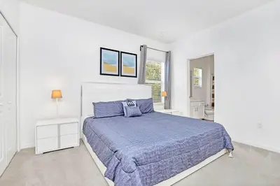 a white bedroom with a large bed with blue sheets at Modern 6BR Home - Pool BBQ Hot Tub - Near Disney in Kissimmee