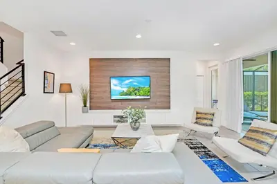 a living room with a couch and a tv on a wall at Modern 6BR Home - Pool BBQ Hot Tub - Near Disney in Kissimmee