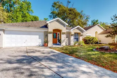 a white house with a driveway at Families with Pets! Home Near Orlando Theme Parks in Orlando