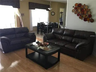a living room with a leather couch and a table at #472-Stunning 5 bed property with private south facing deck and pool in Orlando