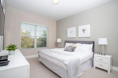 a white bedroom with a large bed and a desk at Dreamscape NEW 4 Suites Villa 5 min to Disney in Orlando