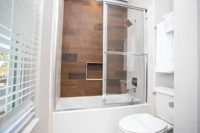 a bathroom with a toilet and a glass shower at Dreamscape NEW 4 Suites Villa 5 min to Disney in Orlando