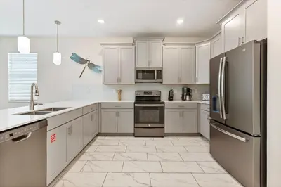a kitchen with white cabinets and stainless steel appliances at New Home 9Bedrooms e 5Bath At Storey Lake in Kissimmee