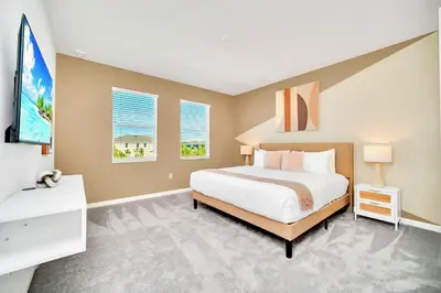 a bedroom with a large bed and two windows at 10BR Resort Home - Pool Hot tub Games - Near Disney in Kissimmee