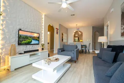a living room with a couch and a tv on a wall at Incredible Condo - 5 Min to Disney Windsor Hills in Orlando