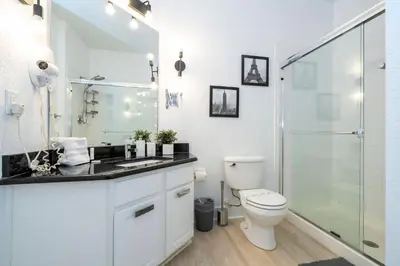 a white bathroom with a toilet and a glass shower at Incredible Condo - 5 Min to Disney Windsor Hills in Orlando