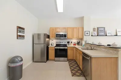 a kitchen with wooden cabinets and stainless steel appliances at Charming 3BR Townhome Private Pool Walk to Clubhouse 9 Min Disney in Orlando