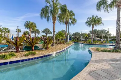 a swimming pool with palm trees in a resort at Lake View - 10 min to Disney Storey Lake Resort in Kissimmee
