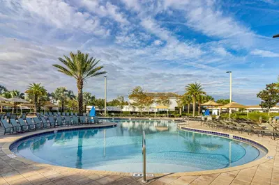 a large swimming pool with chairs and a palm tree at Lake View - 10 min to Disney Storey Lake Resort in Kissimmee