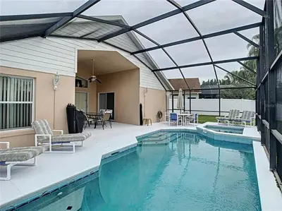a swimming pool with a patio and a house at Magic Orlando Villa, You are in Disney in Kissimmee