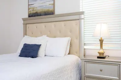 a bedroom with a bed with a blue pillow and a lamp at Exclusive 8BR Family Villa - Pool, BBQ, Game Room & Themed Bedrooms! in Kissimmee