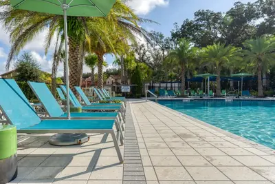 a row of blue lounge chairs next to a swimming pool at Exclusive 8BR Family Villa - Pool, BBQ, Game Room & Themed Bedrooms! in Kissimmee