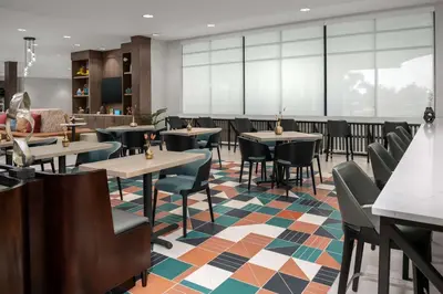 a restaurant with tables and chairs on a colorful floor at Home2 Suites Orlando Southeast Nona in Orlando