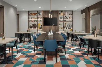a dining room with tables and chairs and a flat screen tv at Hampton Inn Orlando Southeast Nona in Orlando